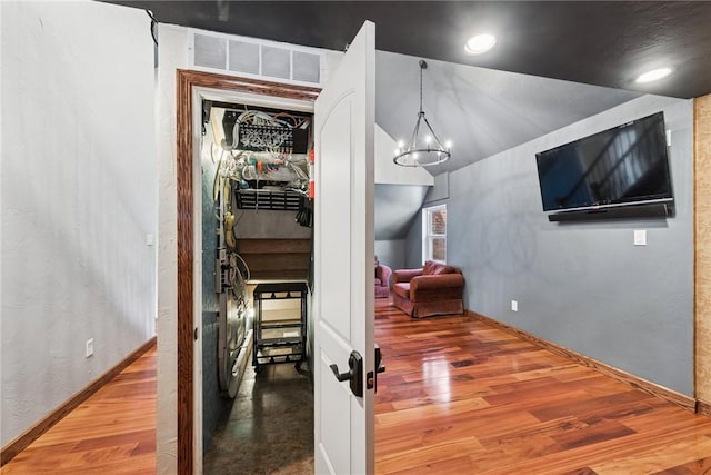 corridor featuring visible vents, baseboards, and wood finished floors