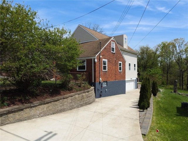 view of side of property with a garage, brick siding, a shingled roof, a lawn, and driveway