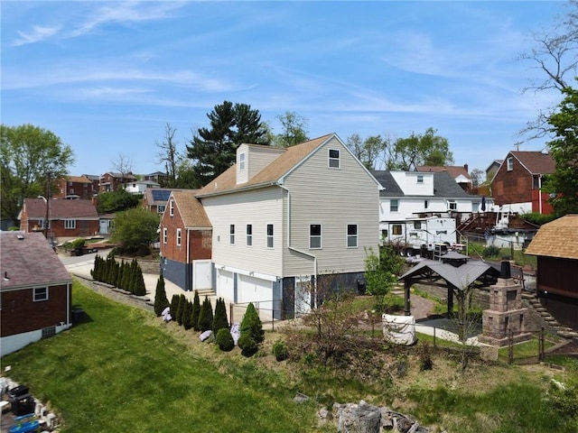 rear view of house featuring a garage, fence, and a residential view