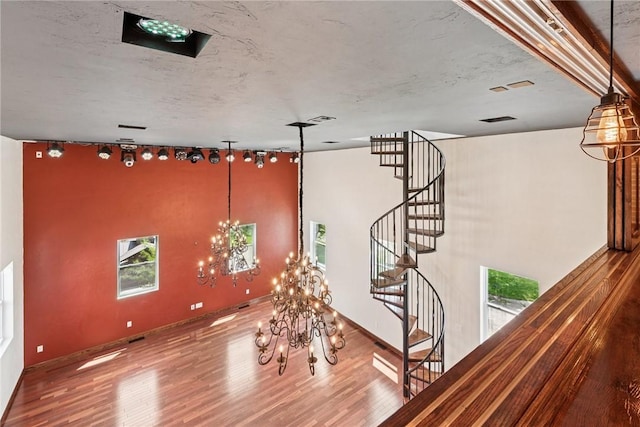 stairs featuring an inviting chandelier, a wealth of natural light, and wood finished floors