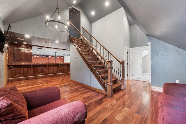 living area featuring visible vents, high vaulted ceiling, stairway, a chandelier, and hardwood / wood-style flooring