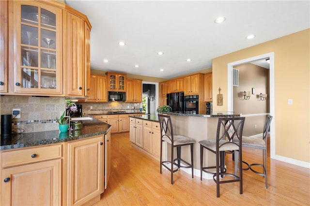 342 Buffalo Ridge Rd, Peters Twp, PA 15317 - kitchen with a breakfast bar area, backsplash, light wood-style flooring, and black appliances