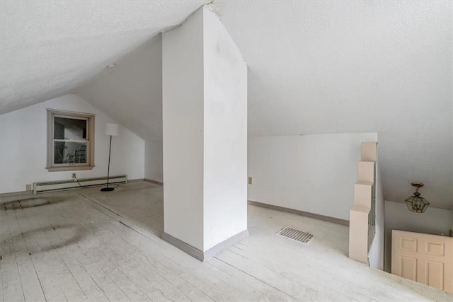 additional living space with vaulted ceiling, visible vents, and a baseboard radiator