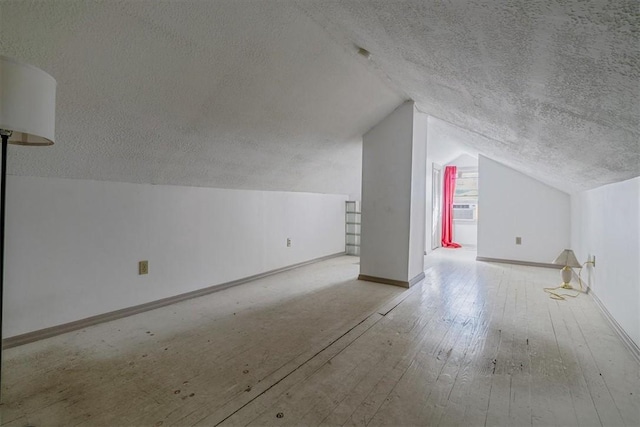 bonus room with hardwood / wood-style floors, baseboards, a textured ceiling, cooling unit, and vaulted ceiling