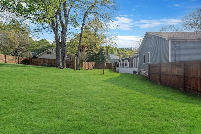 view of yard featuring a fenced backyard and a sunroom