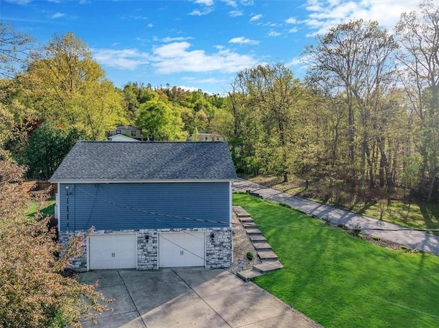 exterior space featuring an attached garage, a forest view, and concrete driveway