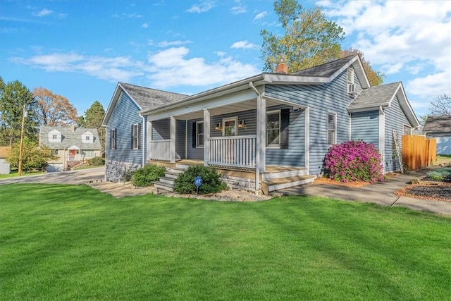 view of front of house with a porch, fence, a chimney, and a front lawn
