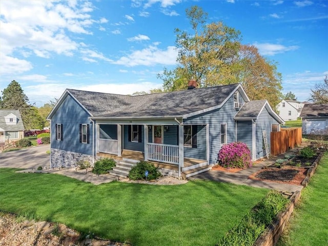 rear view of house with a lawn, fence, a chimney, a shingled roof, and a porch
