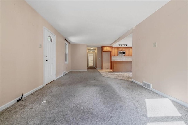 unfurnished living room with light colored carpet, baseboards, and visible vents