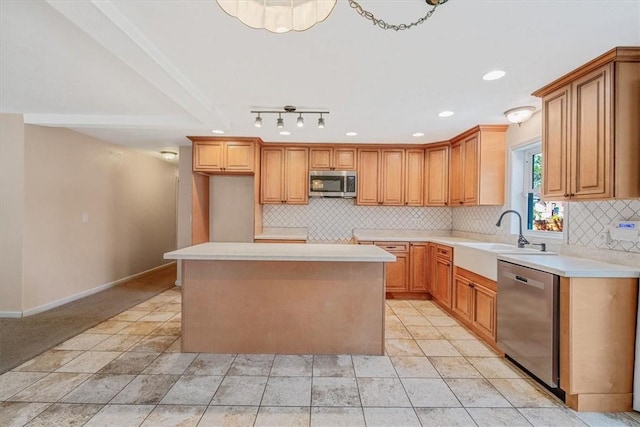 kitchen with appliances with stainless steel finishes, tasteful backsplash, a center island, a sink, and baseboards