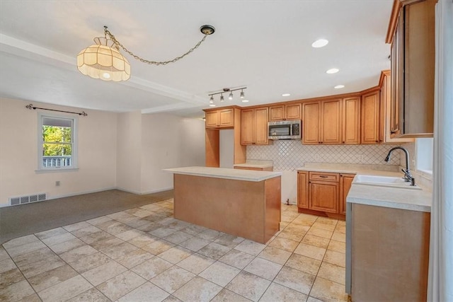 kitchen featuring decorative backsplash, light colored carpet, visible vents, a sink, and stainless steel microwave