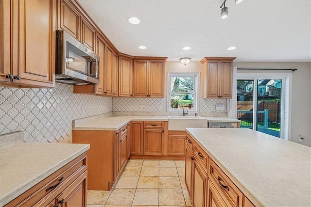 kitchen featuring recessed lighting, light countertops, stainless steel microwave, tasteful backsplash, and a sink