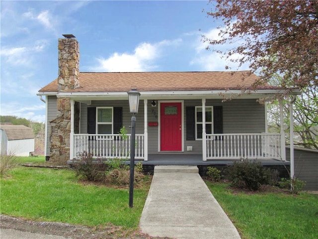 776 W Vine St, Mount Pleasant Boro, PA 15666 - view of front facade with a front lawn, stone siding, covered porch, and a chimney