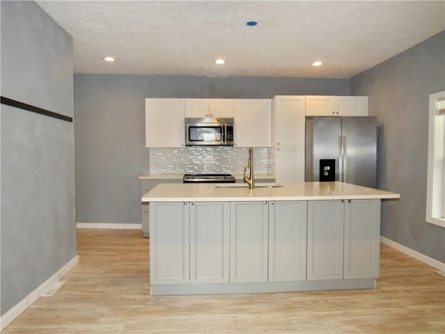 776 W Vine St, Mount Pleasant Boro, PA 15666 - kitchen with a kitchen island with sink, light countertops, a sink, light wood-style flooring, and appliances with stainless steel finishes