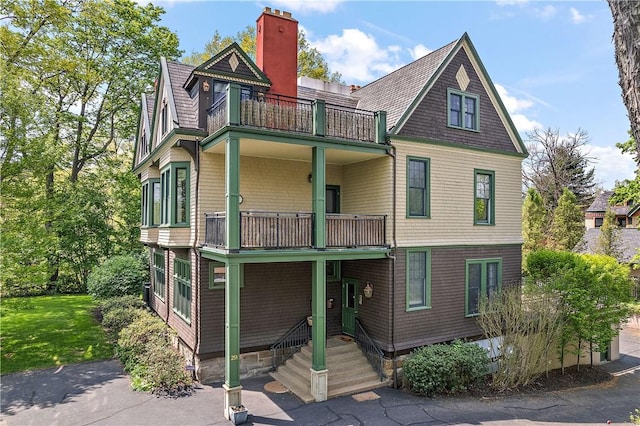 view of front of property featuring a balcony and a chimney