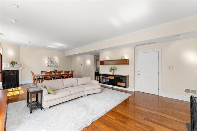 living area with visible vents, crown molding, and wood finished floors
