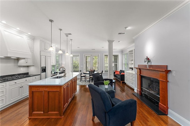 kitchen featuring open floor plan, dark wood-style floors, a fireplace with raised hearth, gas stovetop, and a sink