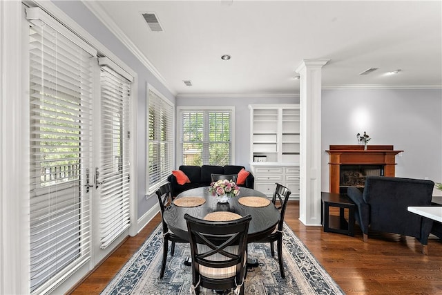 dining area with crown molding, visible vents, wood finished floors, and a fireplace