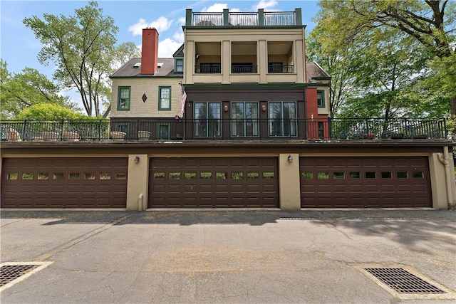 view of front of home featuring stucco siding, a balcony, and a chimney