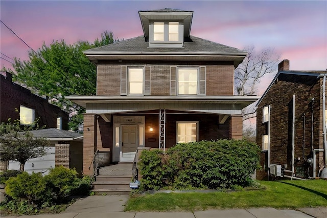 american foursquare style home featuring brick siding and covered porch