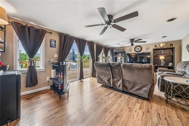 living room with a healthy amount of sunlight, baseboards, ceiling fan, and wood finished floors