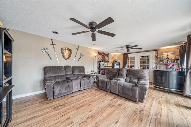 living room with a textured ceiling, french doors, a ceiling fan, baseboards, and wood finished floors