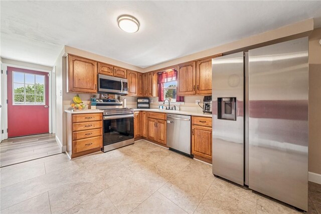 kitchen featuring light countertops, stainless steel appliances, plenty of natural light, and a sink