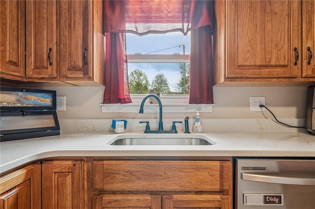 kitchen with a sink, light countertops, stainless steel dishwasher, and brown cabinets