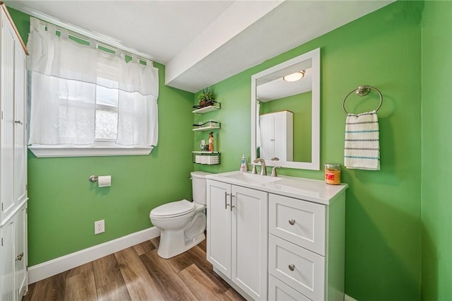 bathroom with baseboards, vanity, toilet, and wood finished floors