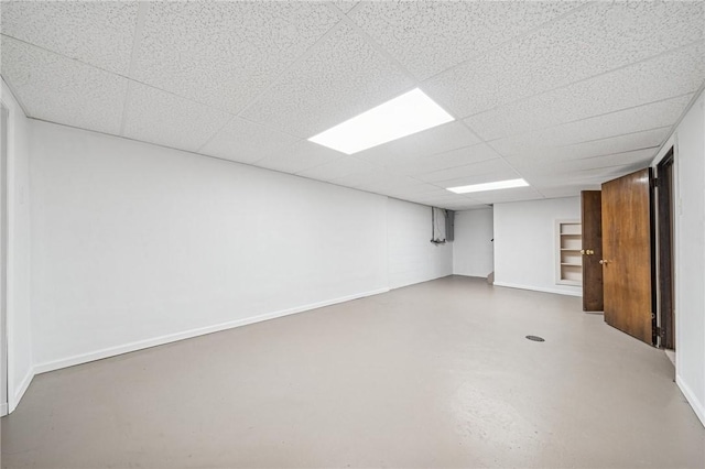 finished below grade area featuring baseboards and a paneled ceiling