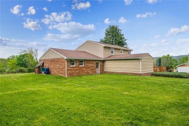 rear view of house with a lawn and brick siding
