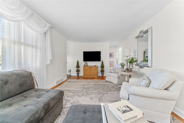 living area with visible vents, baseboards, and wood finished floors