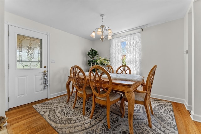 dining area with baseboards, a notable chandelier, and light wood-style flooring