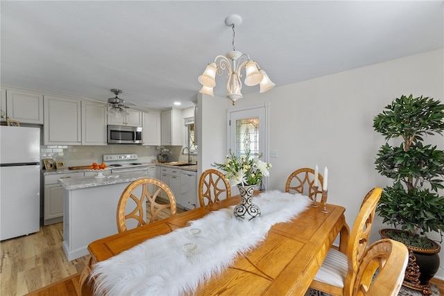 dining space featuring light wood-style floors and ceiling fan with notable chandelier