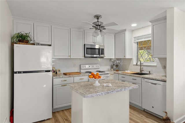 kitchen with a sink, light countertops, light wood-type flooring, and white appliances