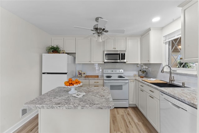 kitchen featuring decorative backsplash, a sink, white cabinets, white appliances, and light wood-style flooring