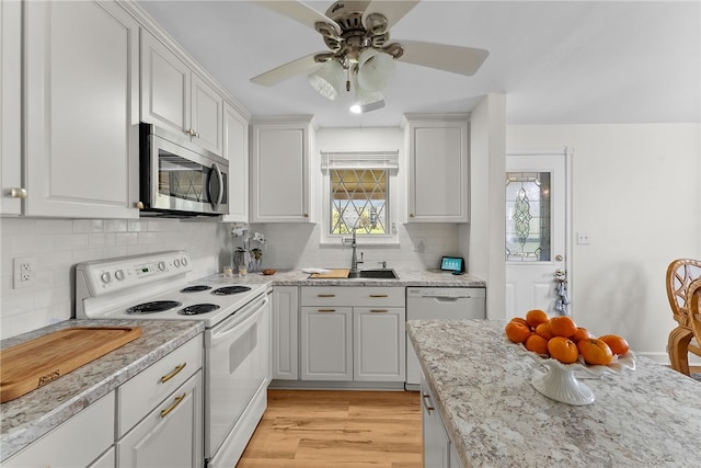 kitchen with decorative backsplash, ceiling fan, a sink, white appliances, and white cabinetry