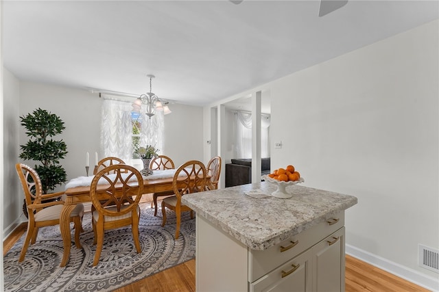 dining room with a chandelier, baseboards, visible vents, and light wood-style floors