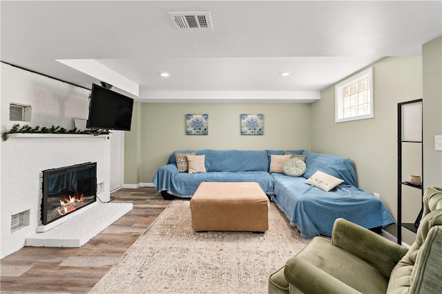 living room featuring visible vents, recessed lighting, a brick fireplace, and wood finished floors