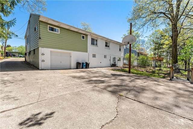 back of property featuring an attached garage, fence, and concrete driveway