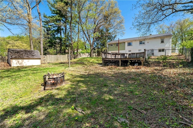 view of yard with a storage unit, a fire pit, a fenced backyard, and a wooden deck
