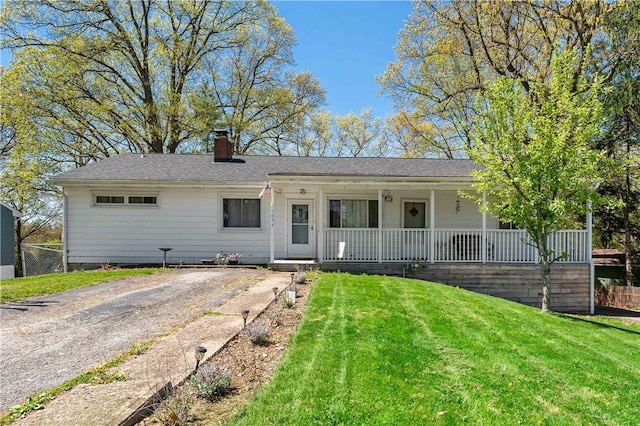 ranch-style house featuring fence, covered porch, a chimney, and a front lawn