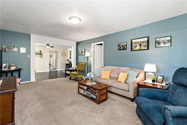 carpeted living area featuring baseboards and ceiling fan
