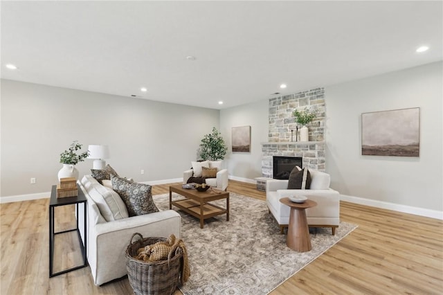living area with recessed lighting, light wood-style flooring, baseboards, and a fireplace