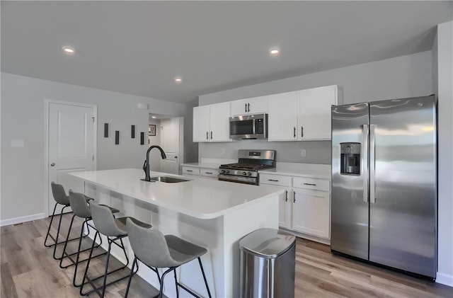 418 Fosse Ct, Lancaster Twp, PA 16037 - kitchen featuring an island with sink, a kitchen bar, a sink, light wood finished floors, and appliances with stainless steel finishes