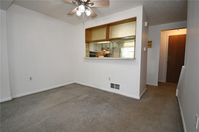 carpeted empty room featuring baseboards, ceiling fan, and visible vents