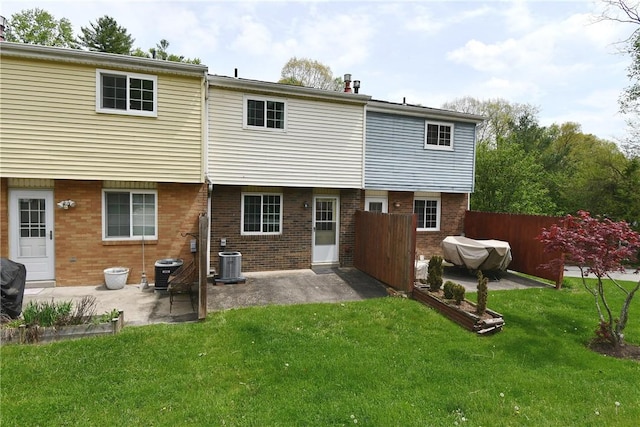 rear view of property with a yard, cooling unit, a patio area, and brick siding