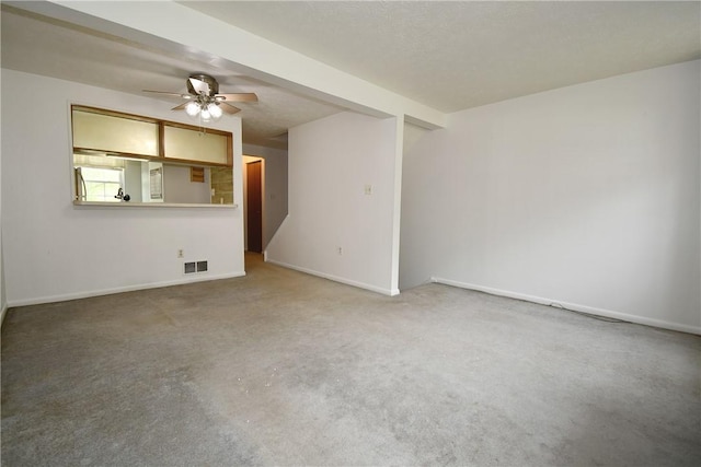carpeted spare room featuring ceiling fan, visible vents, and baseboards