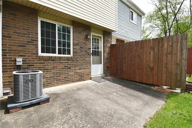 property entrance with brick siding, central AC, fence, and a patio area