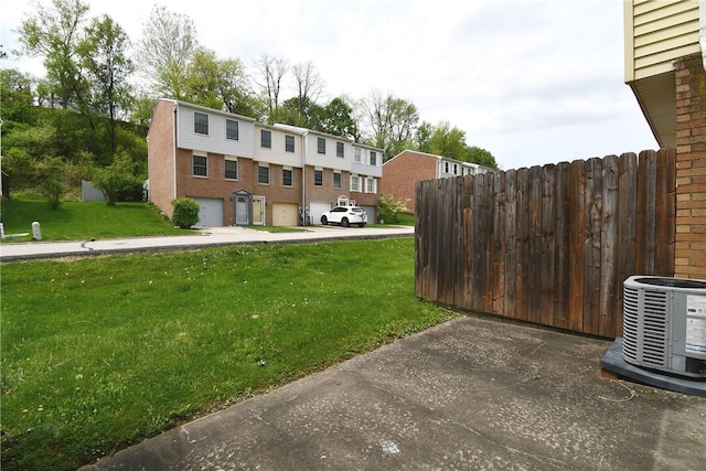 view of yard with a residential view, fence, and central AC